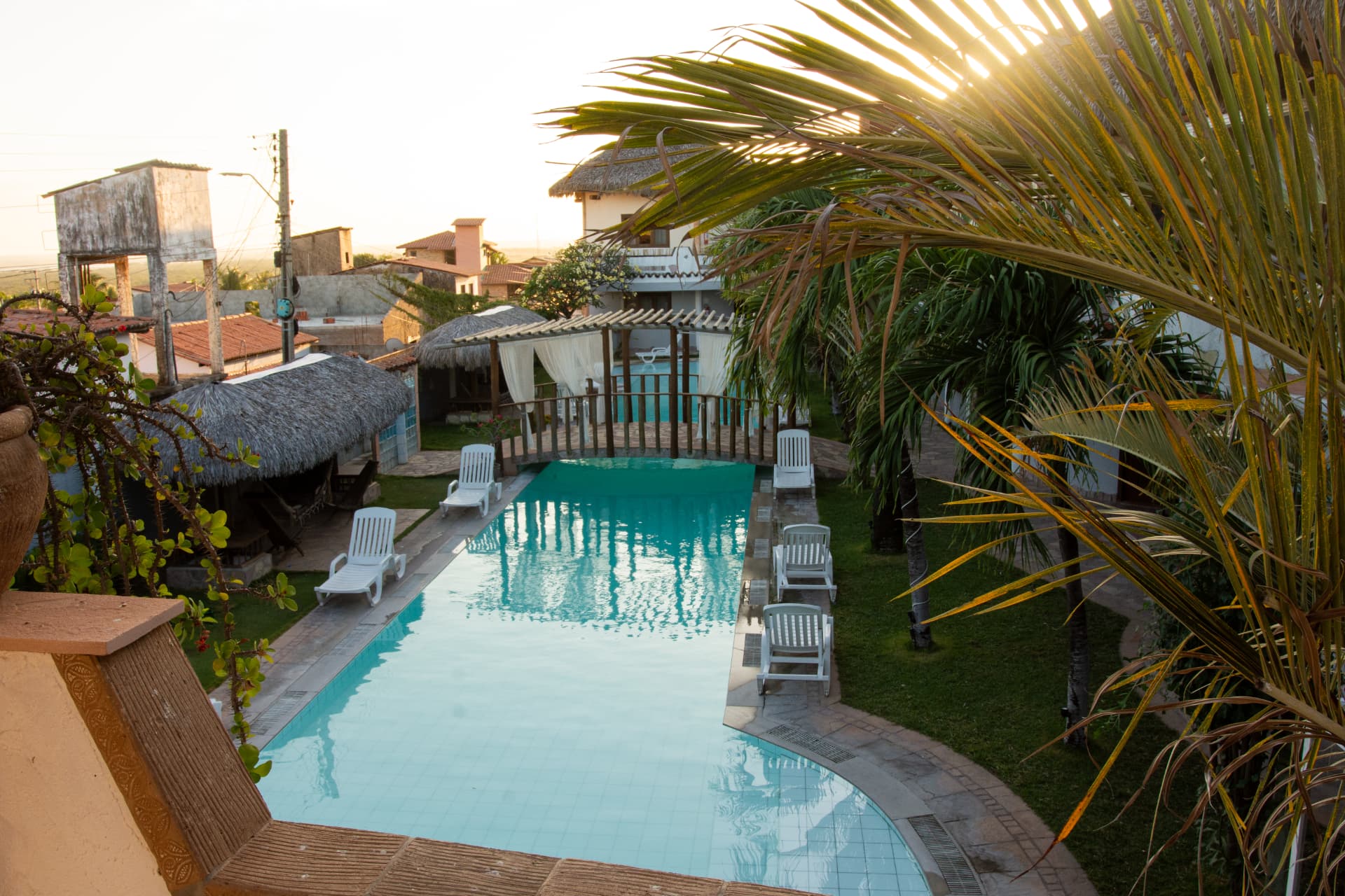 Piscina e jardim tropical do Hotel Il Nuraghe ao entardecer