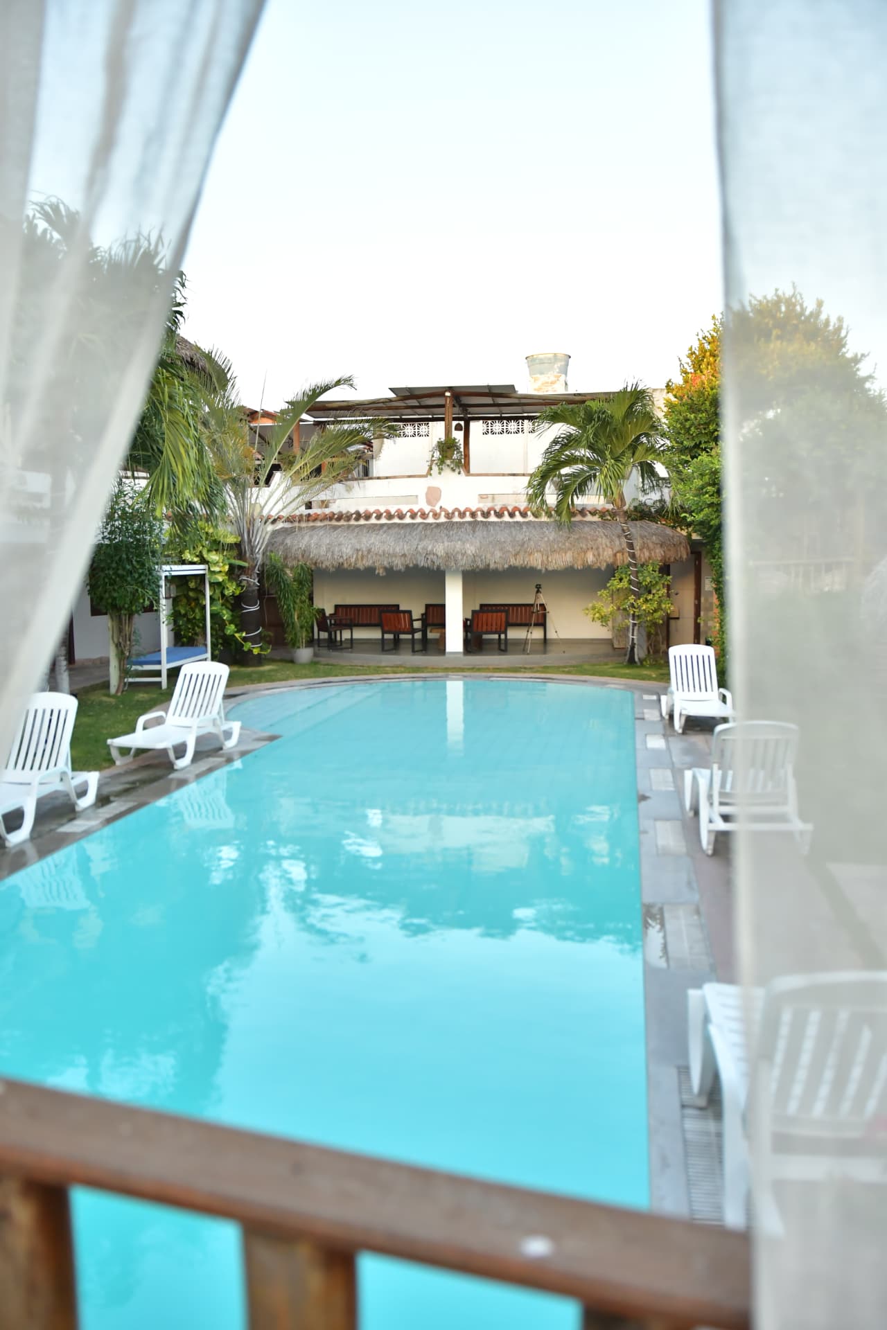 Piscina vista da varanda de um dos quartos, com área de convivência ao fundo